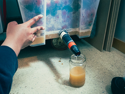 Employee draining biproduct juice from a bokashi bin prototype