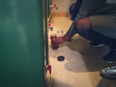 Employee draining biproduct bokashi juice from a large bokashi bin